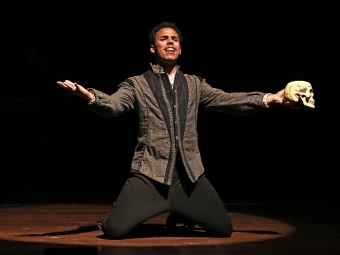 Performer on his knees sings a song while holding a skull