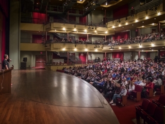 Chartier in frame with large audience seated in front of him