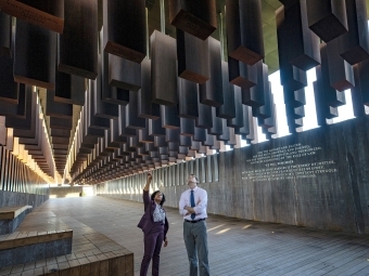 Two people stand and analyze the Equal Justice Initiative Museum exhibit