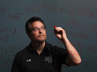 Tim Chartier writes math equations on a glass board