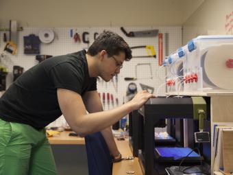 Student by 3D printer in Makerspace