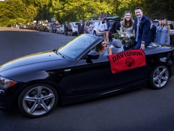 Caroline and Tyler with car lineup behind them 