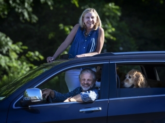 Family with Dog smiling through car 