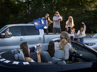 Friends in trunk of truck cheering with sign