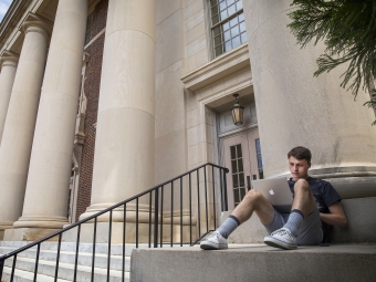 student with laptop on Chambers pillars by steps 