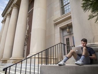 student with laptop on Chambers pillars by steps 