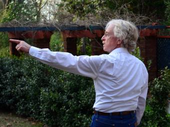 Prof Larry Ligo walking while pointing to art on a tour 