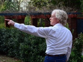 Prof Larry Ligo walking while pointing to art on a tour 