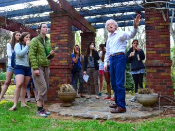 Larry Ligo teaching students in his backyard garden with brick columns and stone path