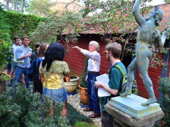 Professor Ligo with Students in His Backyard Garden with trees and statue, small house 
