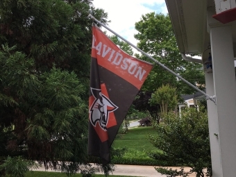 Davidson flag hanging off the side of a house surrounded by trees