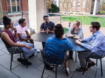 Students talking around a table on the balcony of the Wall Center