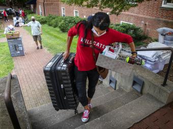 Family Member of Student at Move-In Carries Heavy bag up stairs in mask