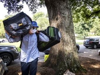 Student Moves in Carrying Two Large Bags on Shoulders Wearing a Mask