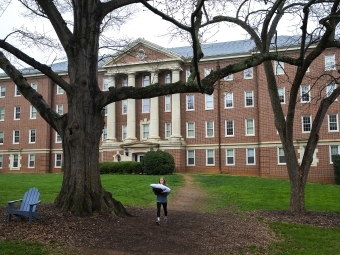 Student carries her pillow out of Tomlinson dorm and an empty campus