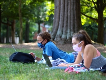 Students on laptops on green with masks