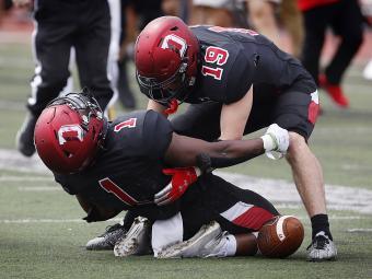 Two Davidson football players helping each other up