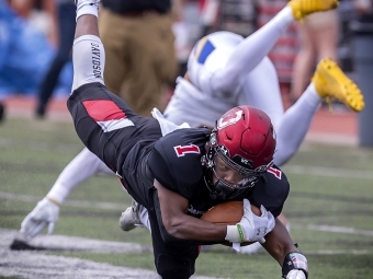 Davidson Football Player Holds Football while Avoiding Tackle