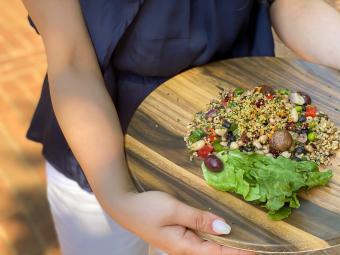 Student holds platter with plant-based meal with veggies and grains