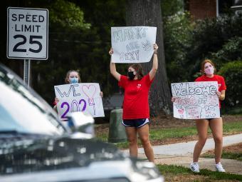 Students in Masks Hold Signs Welcoming New Student Class