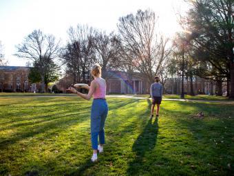 Students in Mask Play Frisbee on Chambers Lawn