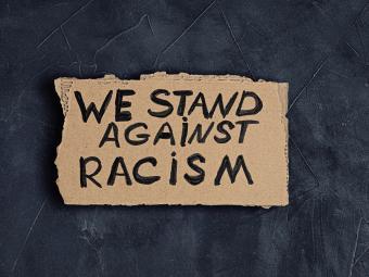 We Stand Against racism sign written on cardboard