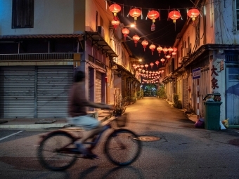 Matt Stirn - A man rides his bike past red lanterns left over from Chinese New Year in the town of Malacca, Malaysia.