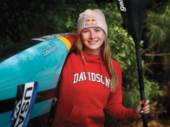 Evy Leibfarth Holding Kayak and Paddle in Davidson College Sweatshirt
