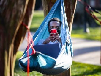 Student on Hammock Studying and on Phone