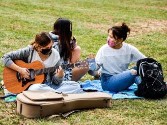 Students Playing Guitar on Lawn with Masks On