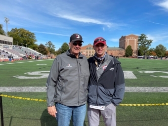 Bazos and Coach Abell Pose in front of football field 