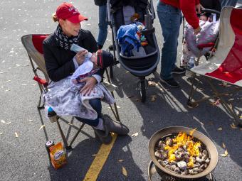 Woman sitting by fire pit feeds baby she is holding a bottle