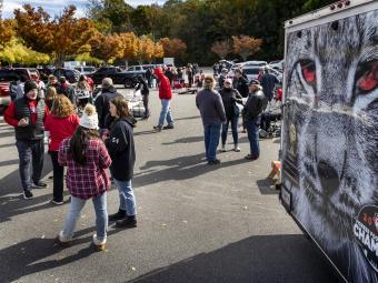 Crowd of students gathered in parking lot near trailer featuring the photo of a Wildcat