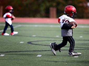 Toddler in Davidson Football Uniform Runs with Ball