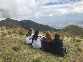 Backs of 4 Davidson students sitting down, looking at scenic mountain view in Ecuador