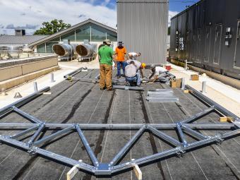 Group of people begin constructing greenhouse on roof of Wall Center