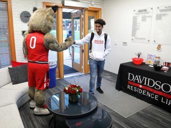 Student Fist Bumps Lux Mascot in RLO Office
