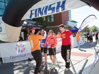 Andrea and David Peet Cross the Finish Line of a Race and are Awarded Medal