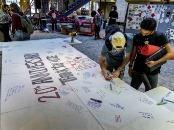 Two students sign thank you note at the 20th anniversary celebration