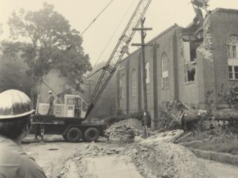black and white photo of construction machine tearing down walls of former Johnston Gymnasium