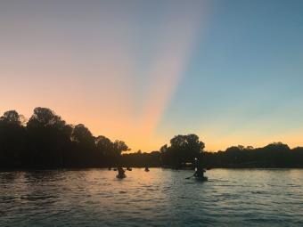 The lake at sunset with kayakers in silhouette