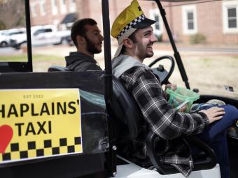 Students in Golf Cart with Taxi Hat and Sign saying "Chaplains Taxi"