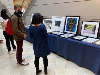 students and director around table of artwork displayed