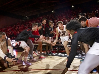 basketball player running onto court high-fiving players lined up on both sides