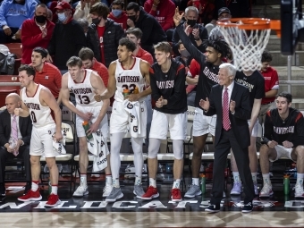 Davidson basketball players and Coach McKillop cheering on sidelines at a game