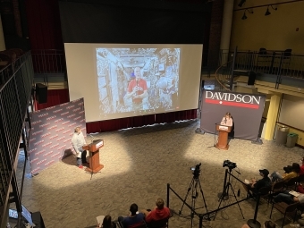 two students speak into microphones with Tom Marshburn on a projector screen