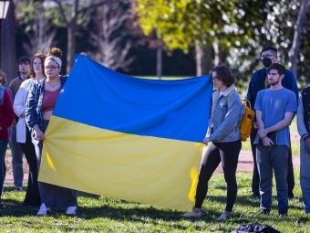 Students gathered holding Ukraine flag outside for on-campus vigil