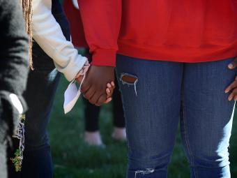 two students hold hands together at vigil for Ukraine on campus
