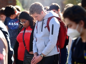 students looking down during vigil for Ukraine on campus