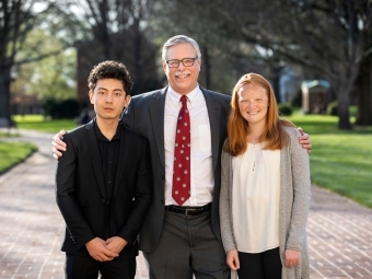 Prof. Emeritus Rich Neidinger outside with two student inductees on his left and right
